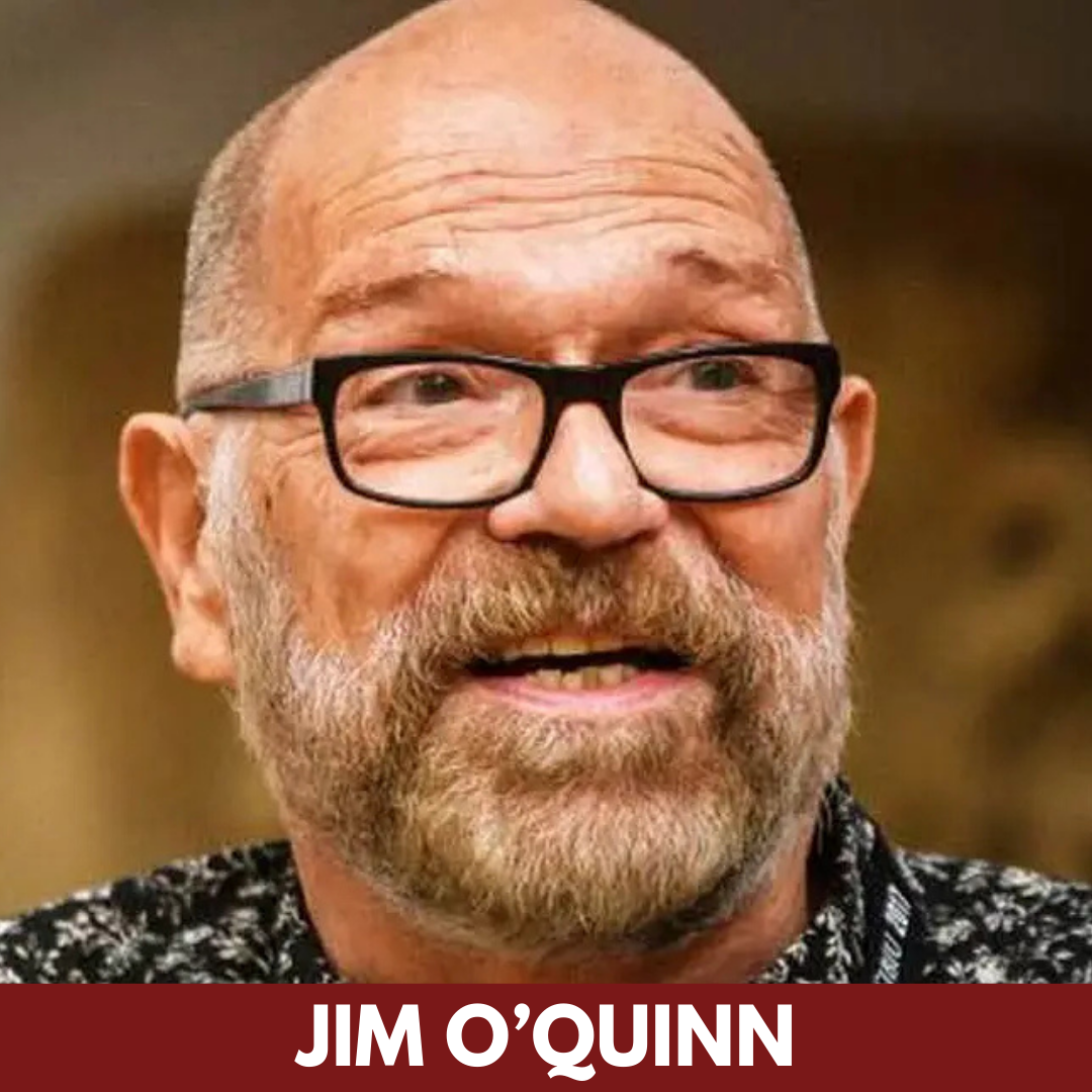 An older man with dark-rimmed glasses looks up.